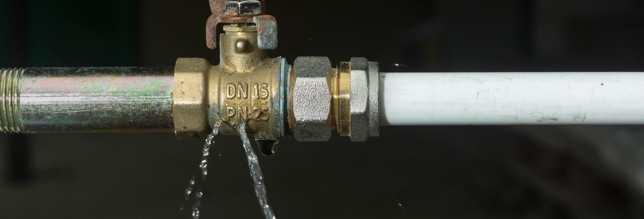 Dettaglio di un tubo con rubinetto da cui esce dell'acqua