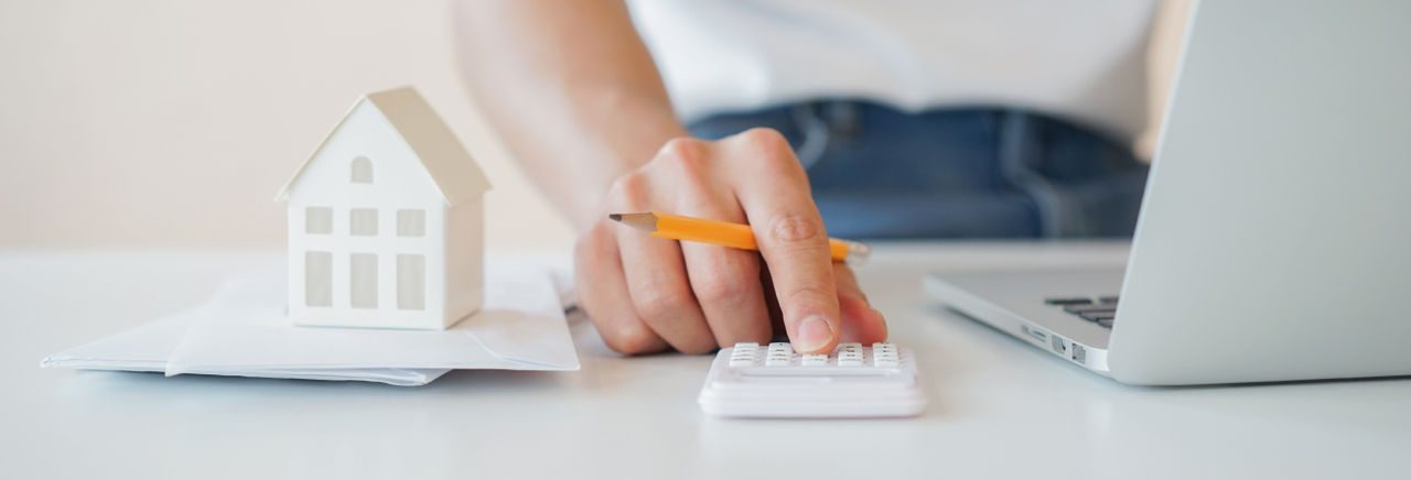 Mano di una ragazza che utilizza una calcolatrice con accanto un pc