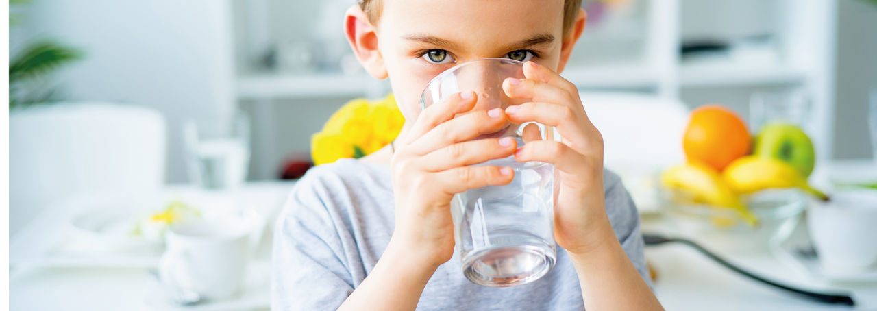 Bambino guarda in camera nel mentre che beve acqua 