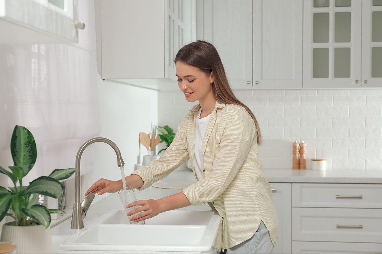 ragazza riempie bicchiere d'acqua al rubinetto