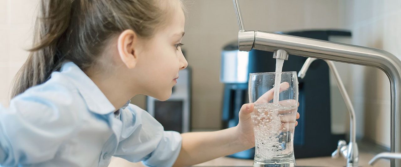 bimba riempie bicchiere d'acqua al rubinetto