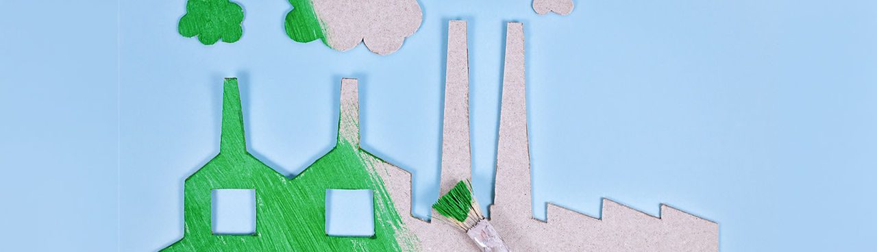 Il concetto di “greenwashing” illustrato da una fabbrica di cartone dipinta di verde