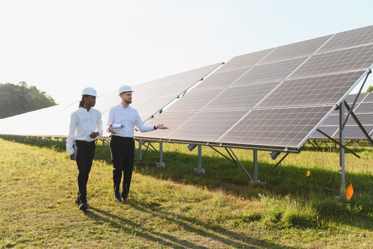Ingegneri che indossano cappelli duri e discutono di soluzioni di energia rinnovabile in un grande parco solare