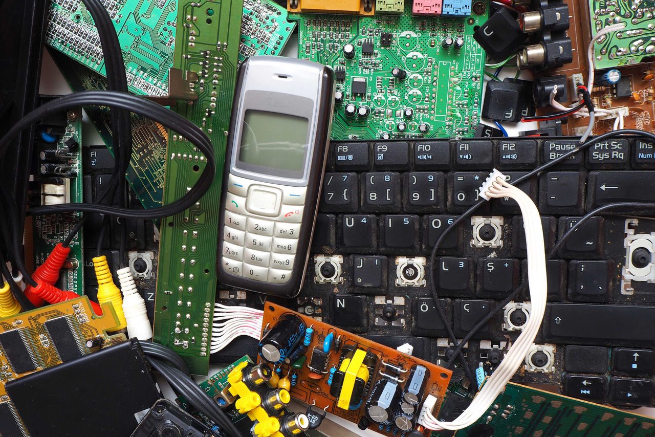 in foto sono rappresentati numerosi rifiuti RAEE, tra cui una tastiera rotta di un computer e un telefonino degli anni 2000