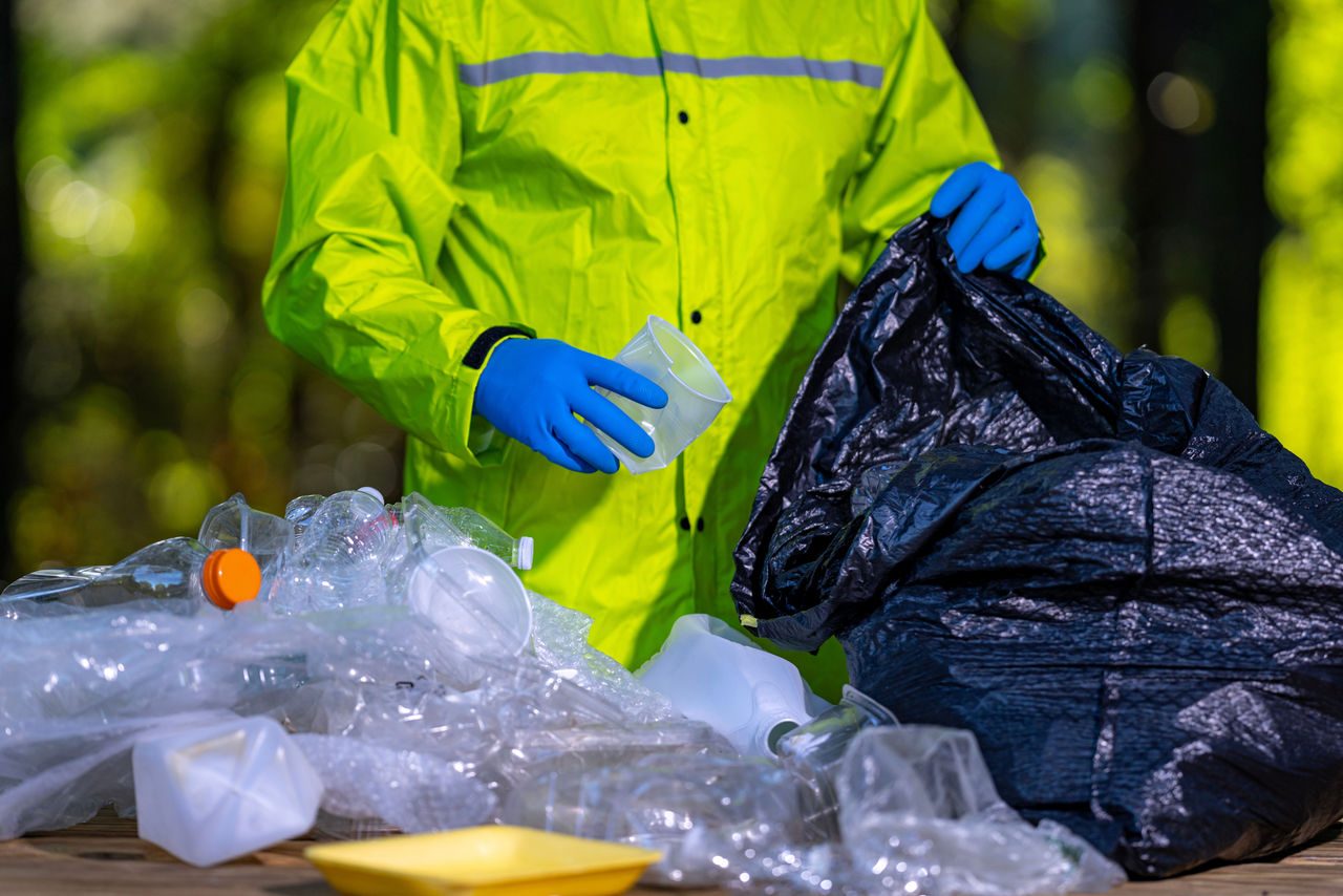 addetto allo smistamento raccoglie rifiuti di plastica in una busta dell'immondizia