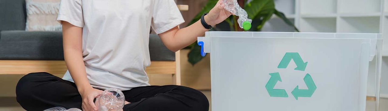 mezza fiura di ragazza intenta a gettare nel contenitore di rifiuti riciclabili una bottiglia di plastica