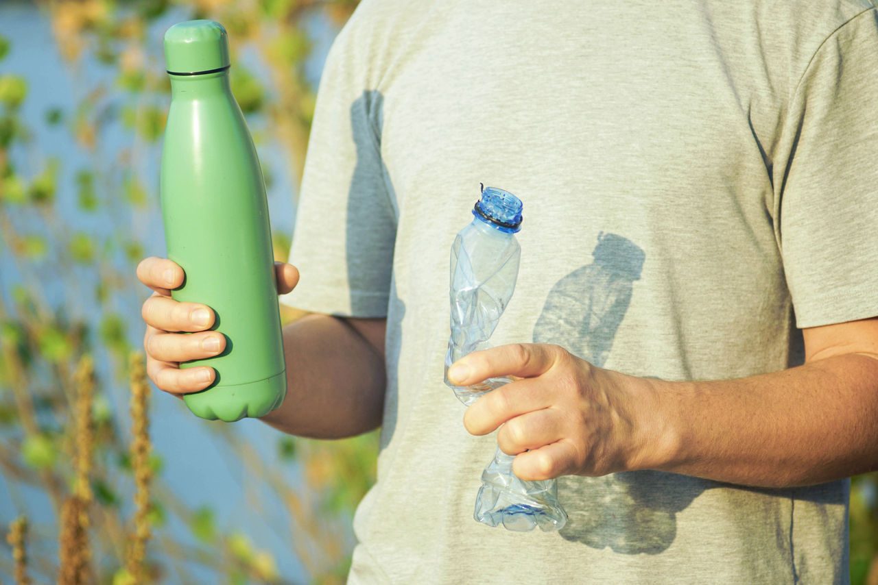 ragazza ecoconsapevole che sceglie la bottiglia d'acqua riutilizzabile rispetto alla plastica monouso