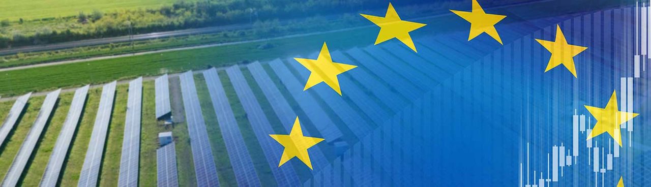 Bandiera dell'Europa in sovraimpressione sfumata e sullo sfondo impianti fotovoltaici
