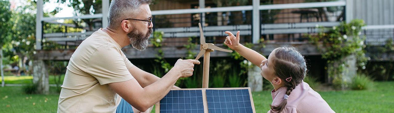 papà e figlia giocano con un modello di pale eoliche