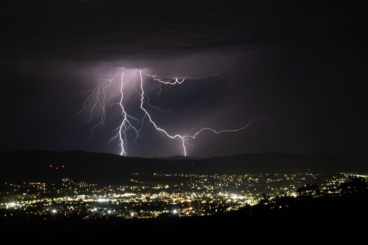 Fulmini in un cielo notturno con luci città