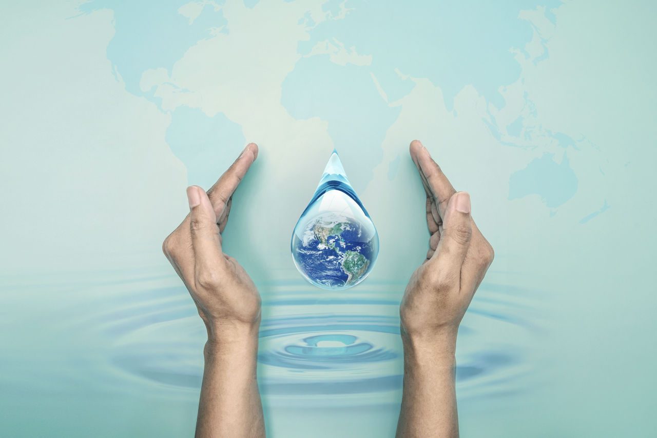 Due mani che circondano un globo terrestre a forma di goccia d'acqua. 