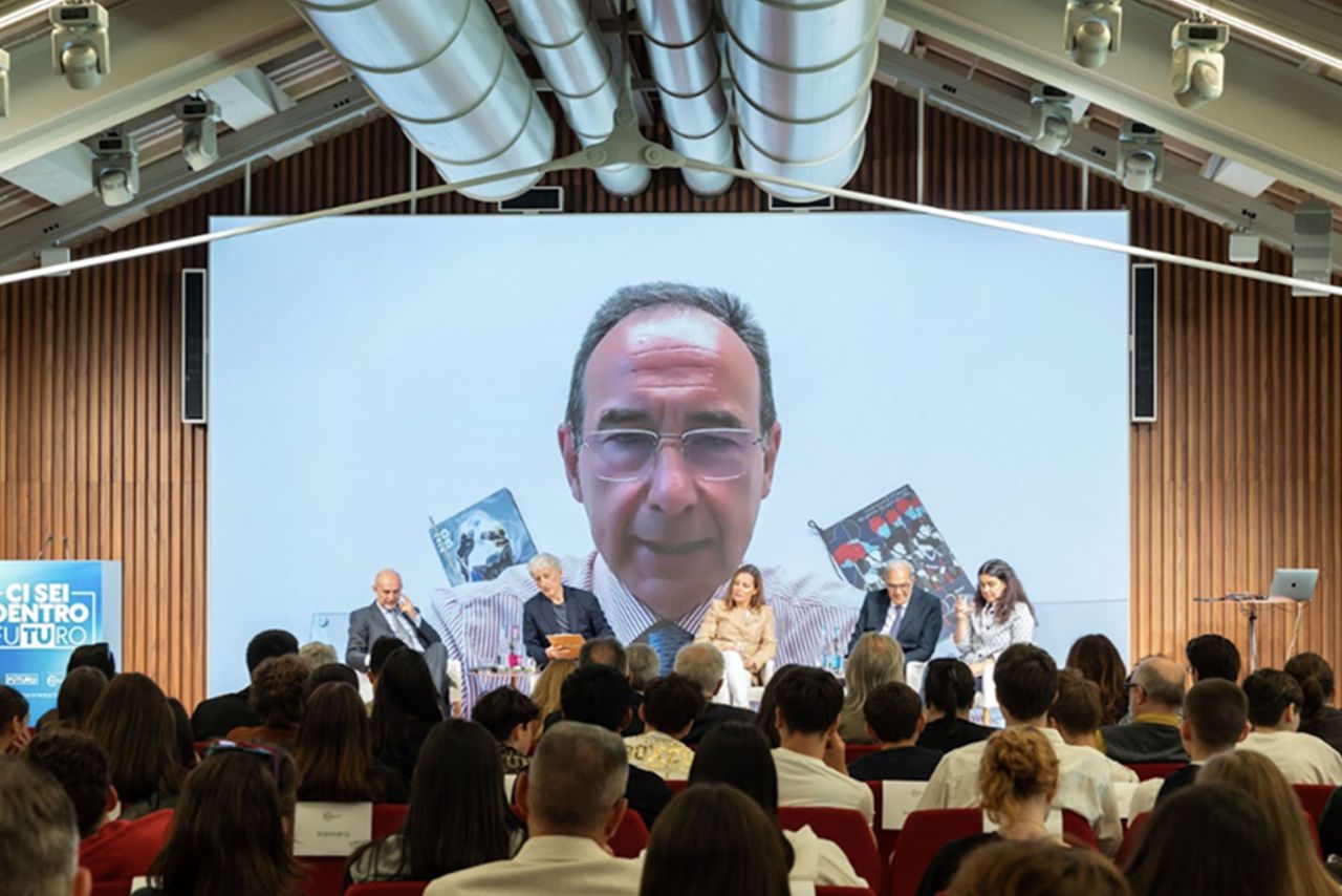 Un momento del convegno con il pubblico in sala e Luca Dal Fabbro collegato da remoto proiettato su uno schermo gigante, durante l'evento "Ci sei dentro il futuro".