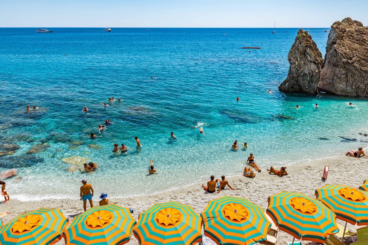persone in acqua che si fanno il bagno e sulla spiaggia ombrelloni colorati