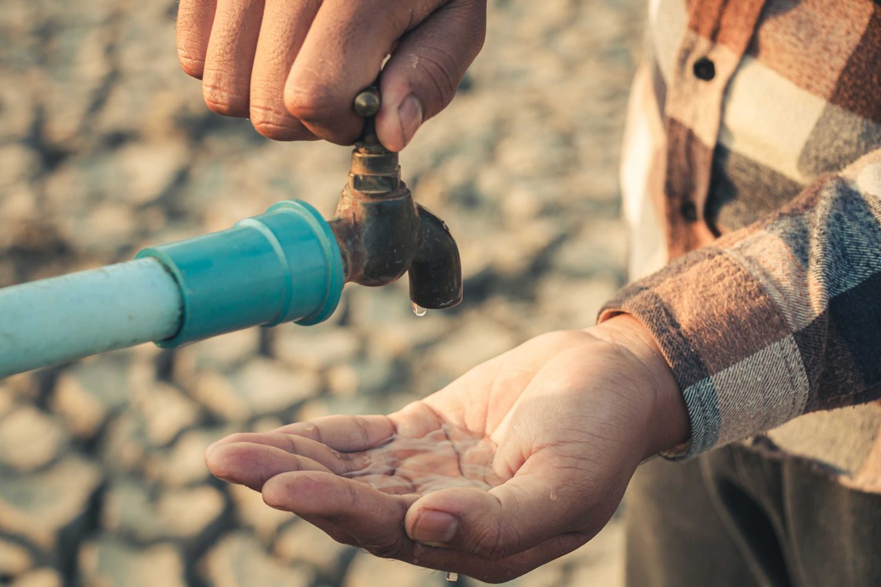 uomo che tiene palmo di mano sotto rubinetto che perde acqua