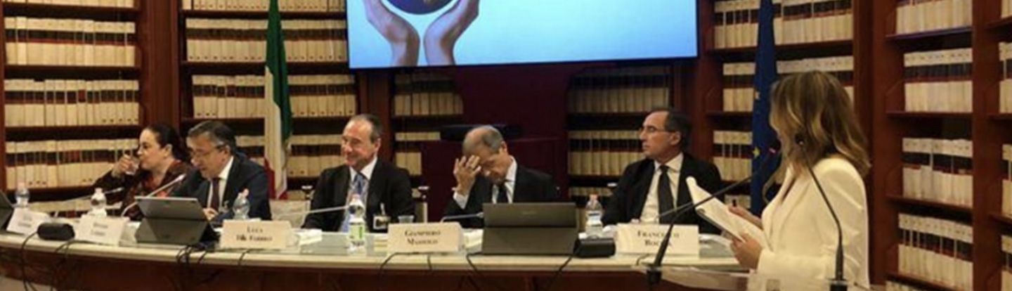 Evento di presentazione del libro in un’aula istituzionale, con relatori seduti al tavolo e la copertina del volume proiettata sullo schermo.