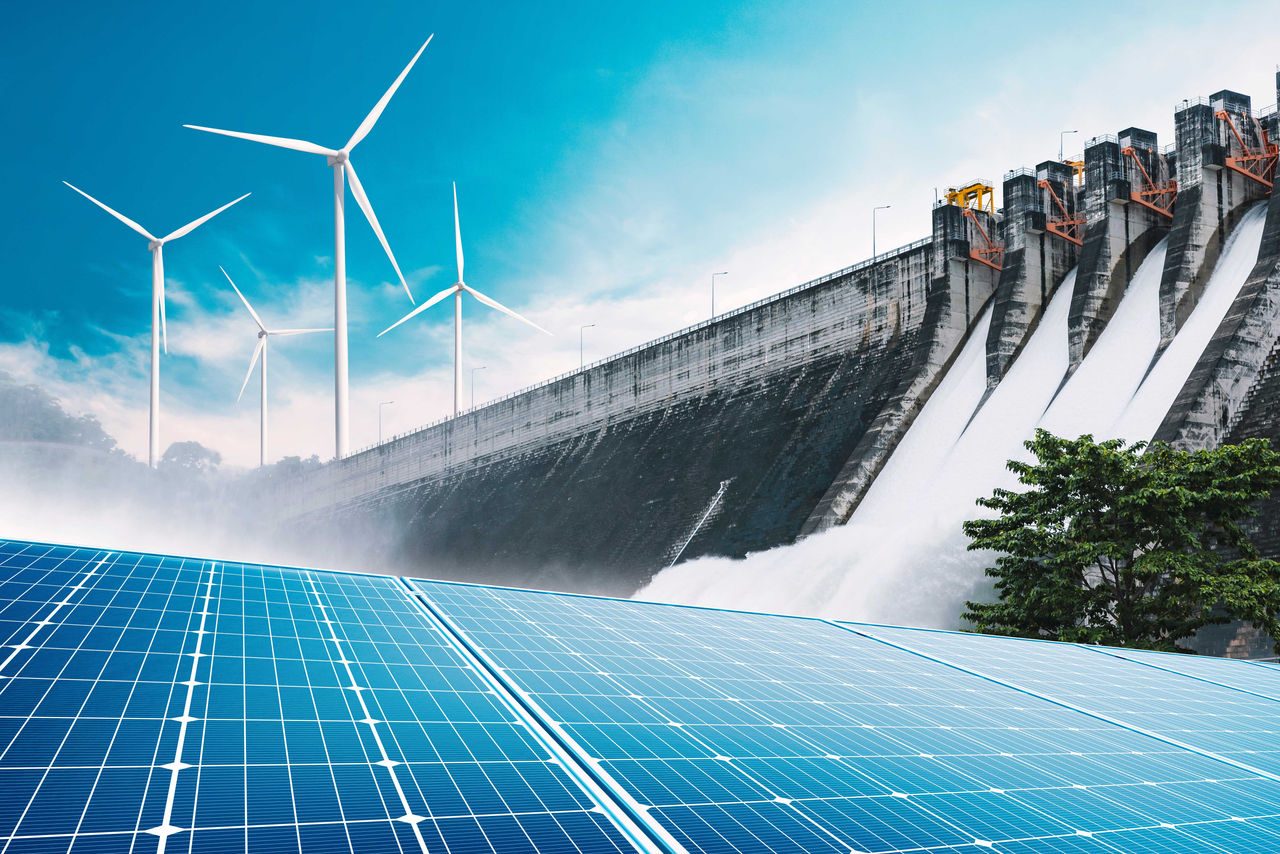pannelli fotovoltaici con diga e pale eoliche sullo sfondo