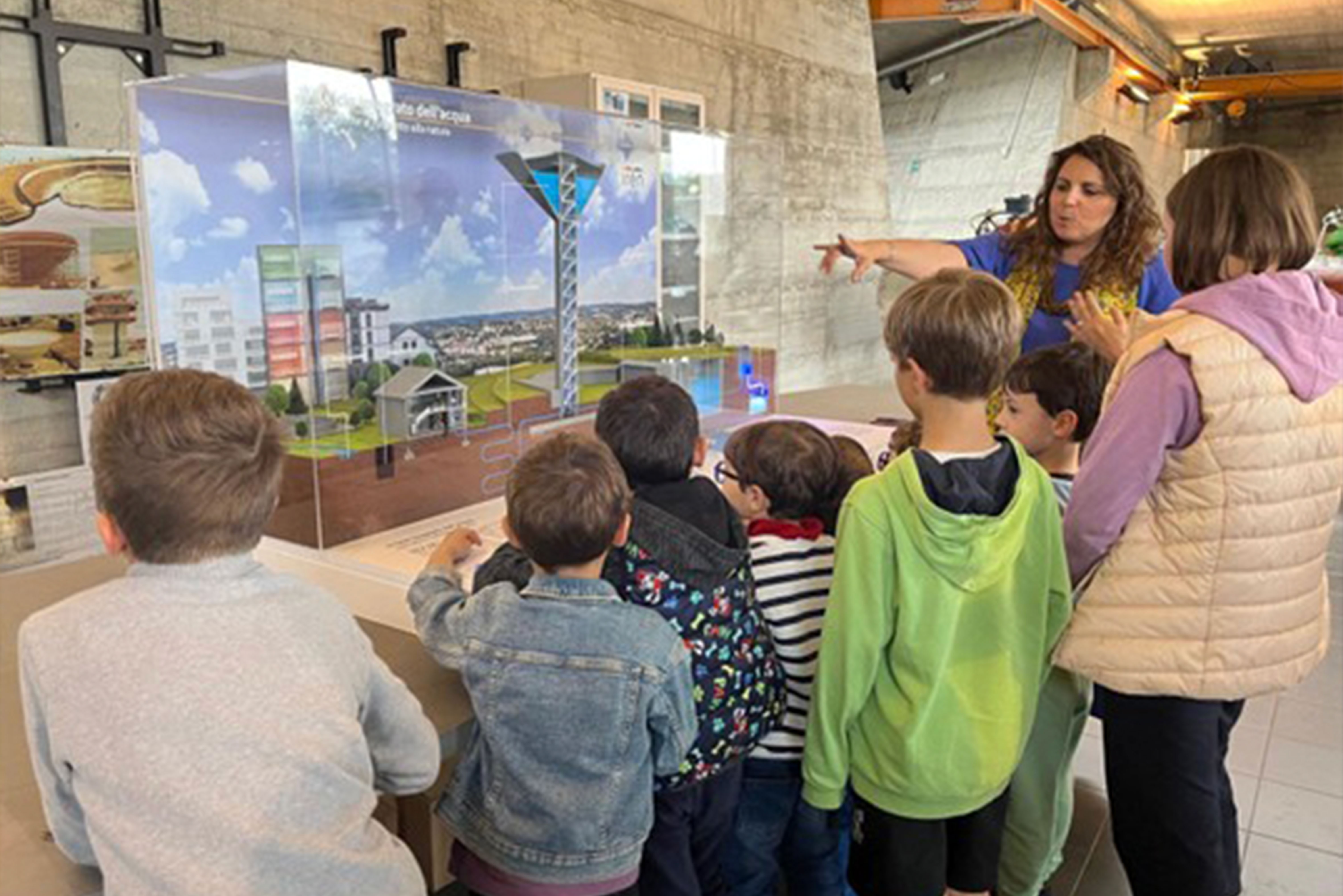 Gruppo di bambini ascolta una guida davanti a un plastico che rappresenta il ciclo dell’acqua.
