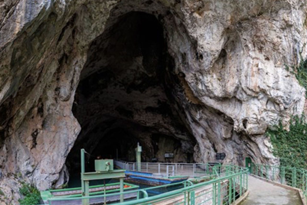  Ingresso di una grotta rocciosa che ospita un impianto idrico con passerelle e strutture metalliche, utilizzato per la gestione delle acque.