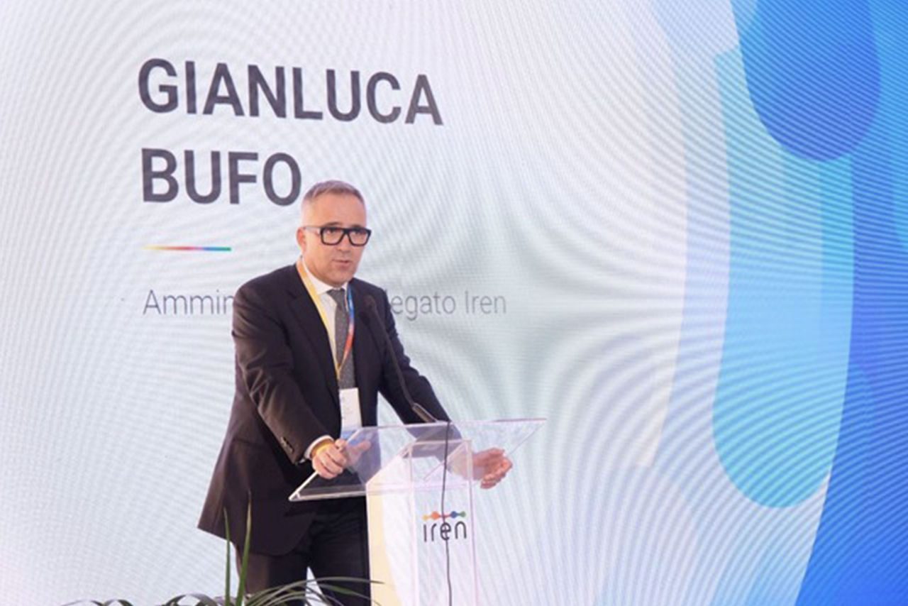  Gianluca Bufo, Amministratore Delegato di Iren, tiene un discorso su un palco con un grande schermo alle sue spalle che riporta il suo nome e la sua carica.