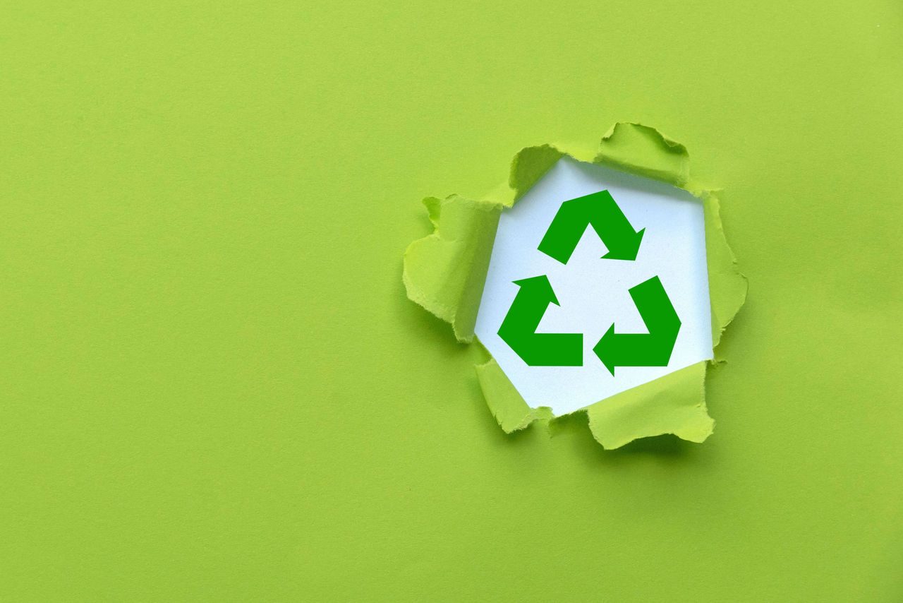 Icona riciclo che spunta da sfondo verde 