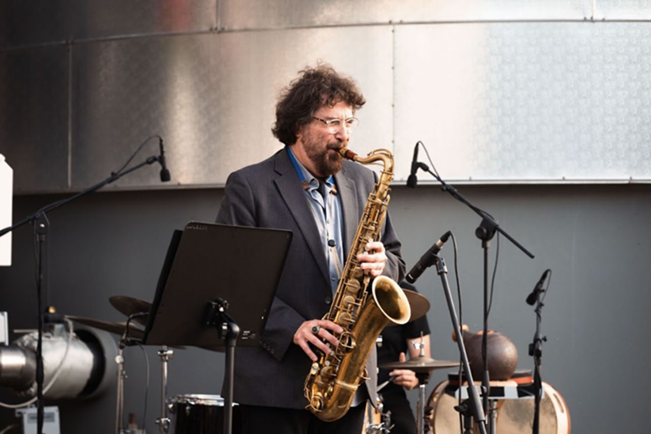Un musicista suona il sassofono durante una performance jazz all’interno del termovalorizzatore Iren, con microfoni e strumenti sullo sfondo.