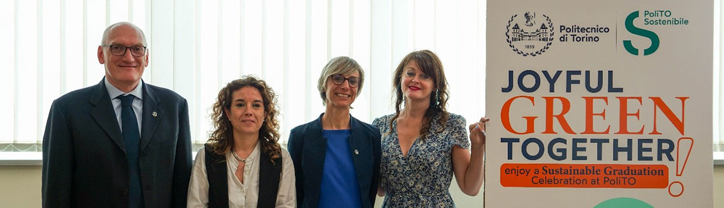 Quattro rappresentanti del Politecnico di Torino in posa accanto al manifesto dell’iniziativa "Joyful Green Together" per una laurea sostenibile.