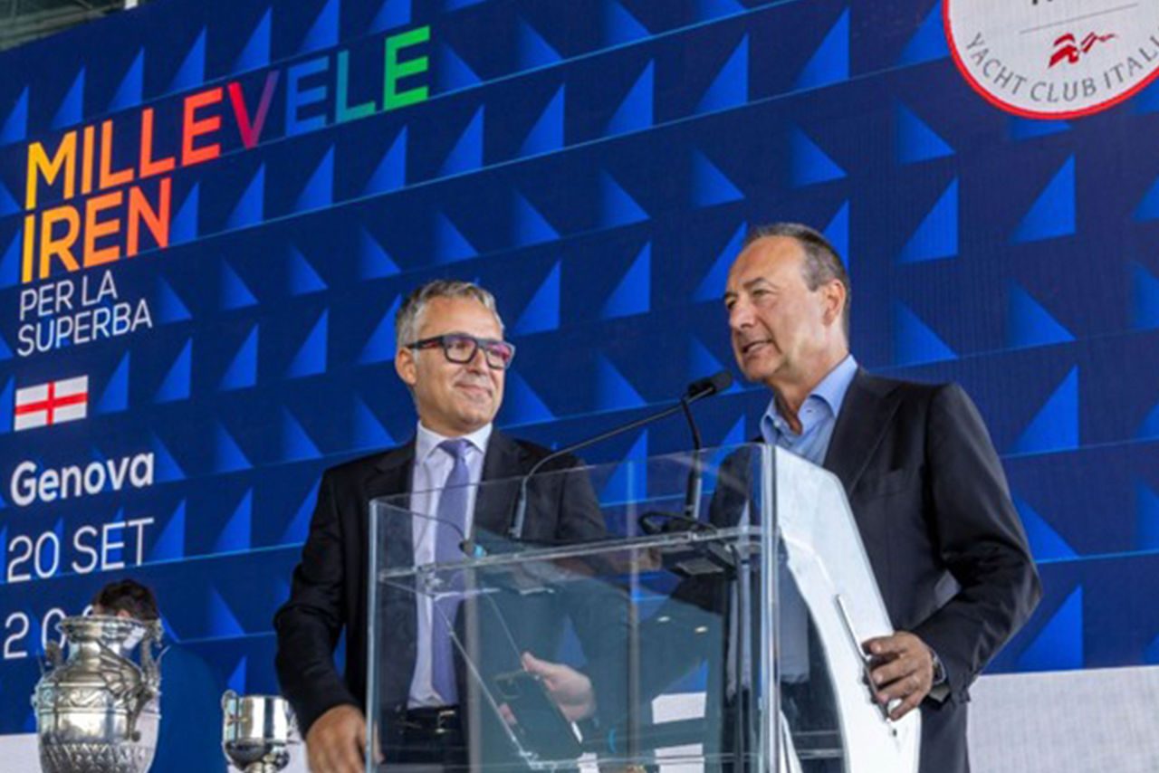 Luca Dal Fabbro e un altro rappresentante istituzionale parlano dal podio in vetro durante l’evento Millevele Iren, con lo schermo alle spalle che mostra la data del 20 settembre 2025 e i loghi di Iren e Yacht Club Italiano.