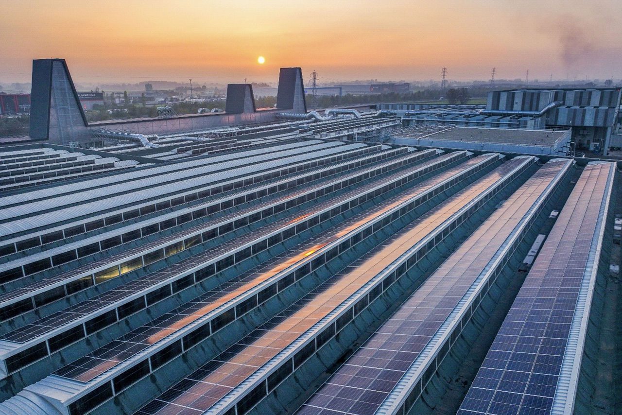 Vista aerea di un impianto industriale Iren con pannelli solari sul tetto al tramonto.