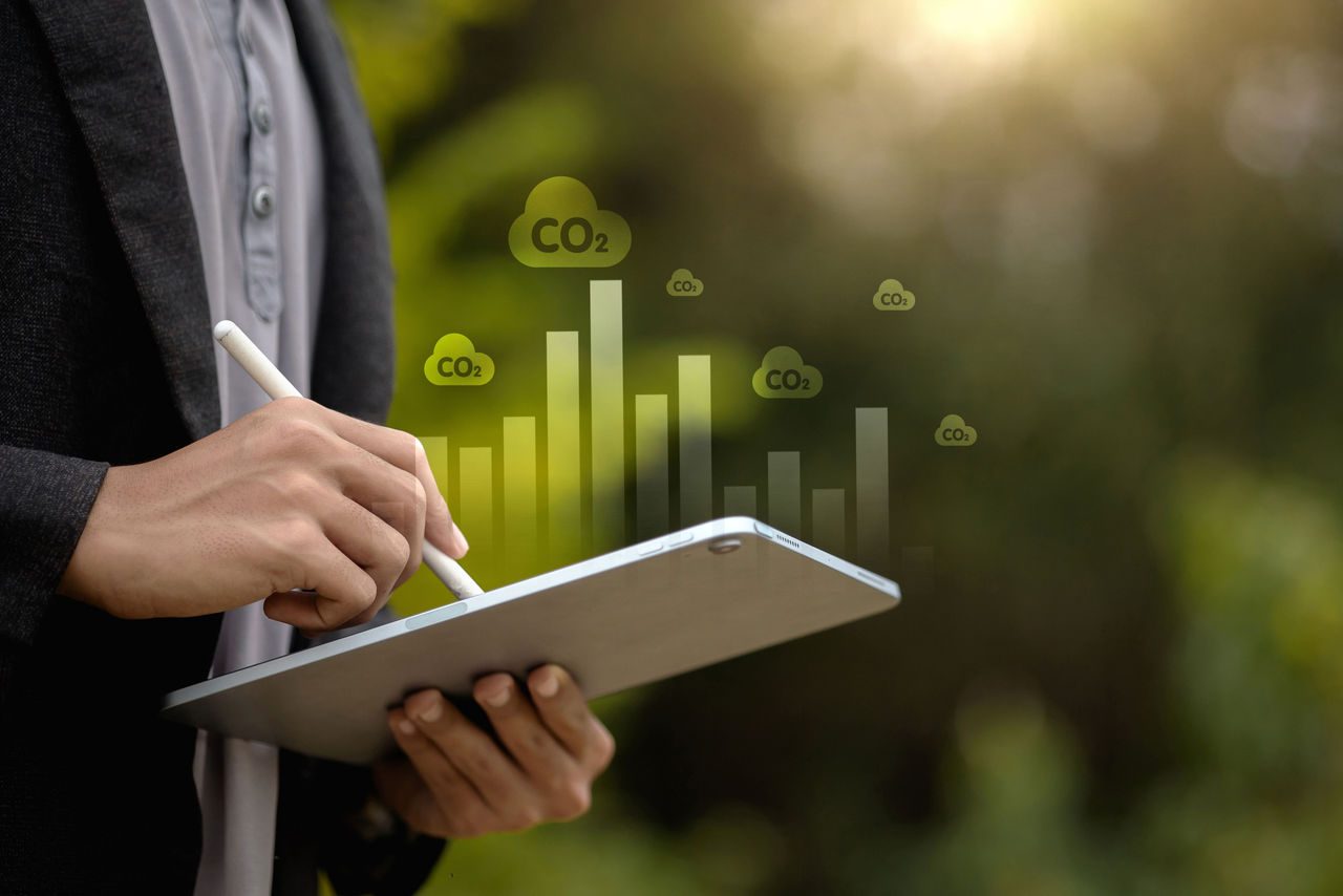 Uomo d'affari che utilizza tablet con dashboard di analisi delle emissioni di CO2