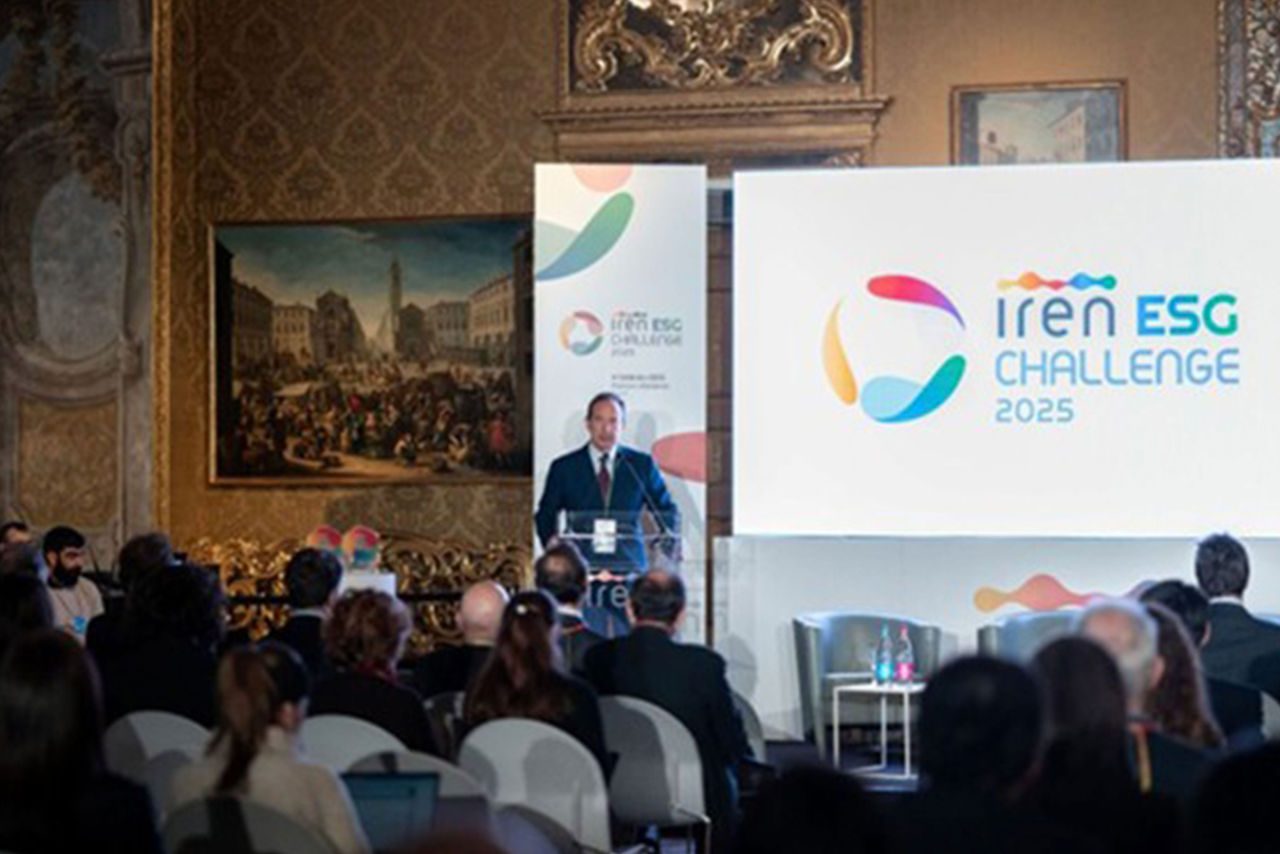 Luca Dal Fabbro interviene sul palco dell’Iren ESG Challenge 2025, durante una conferenza ospitata in una sala storica decorata con quadri e stucchi. Sullo sfondo il grande schermo mostra il logo ufficiale dell’evento.