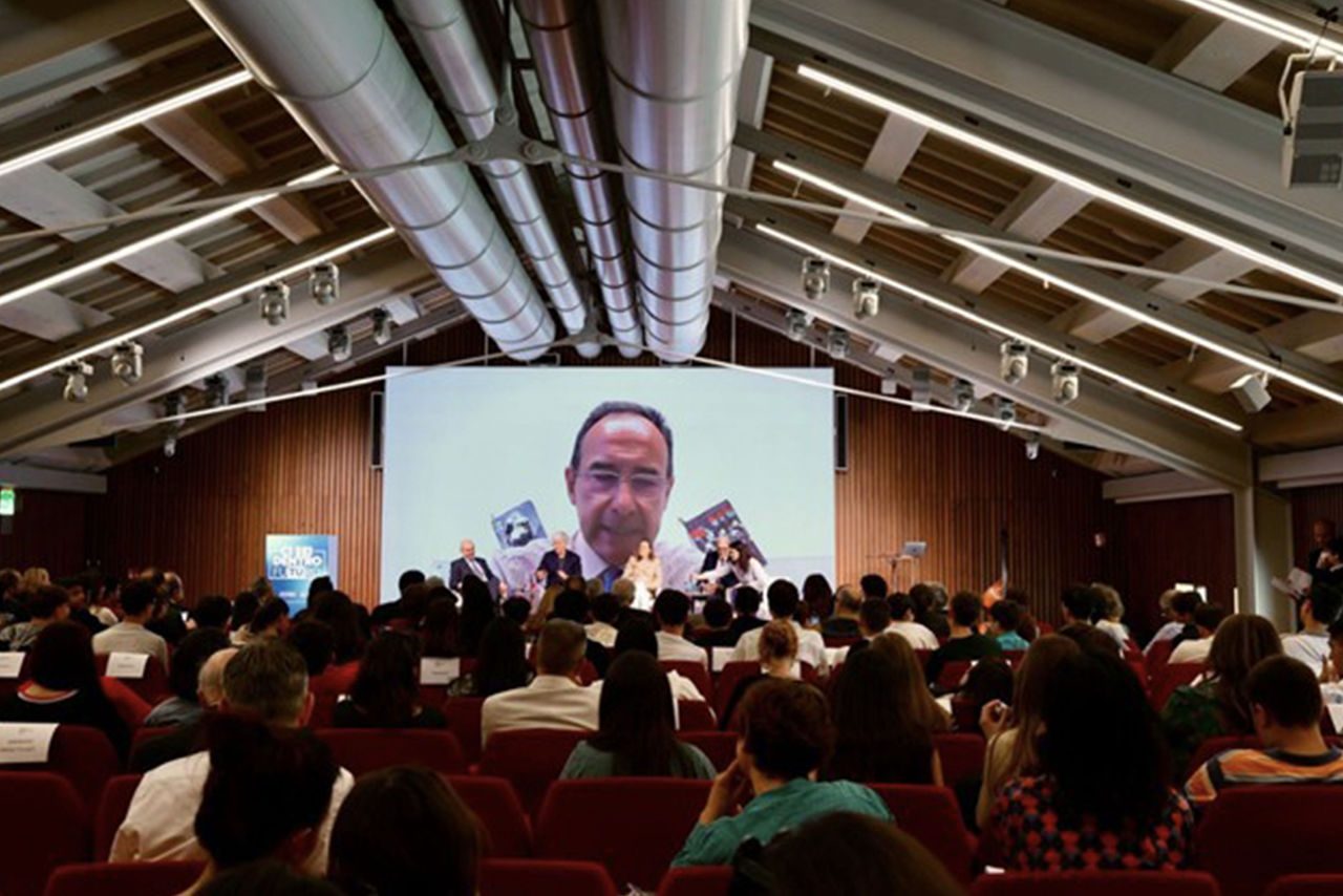 Evento Future Day 2025 con proiezione su maxischermo – Una sala gremita di partecipanti assiste a un incontro con Luca Dal Fabbro in video collegamento.