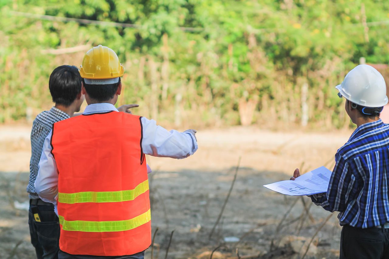 un team di architetti e ingegneri discute per progettare costruzione su larga scala che soddisfino le loro esigenze e ne esamina la fattibilità