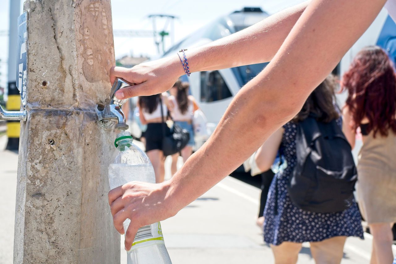 un uomo riempie la sua bottiglia d'acqua presso una fontanella