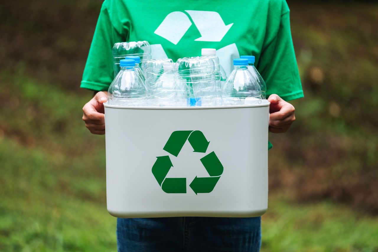 ragazza che tiene in mano un contenitore per il ricliclo della plastica