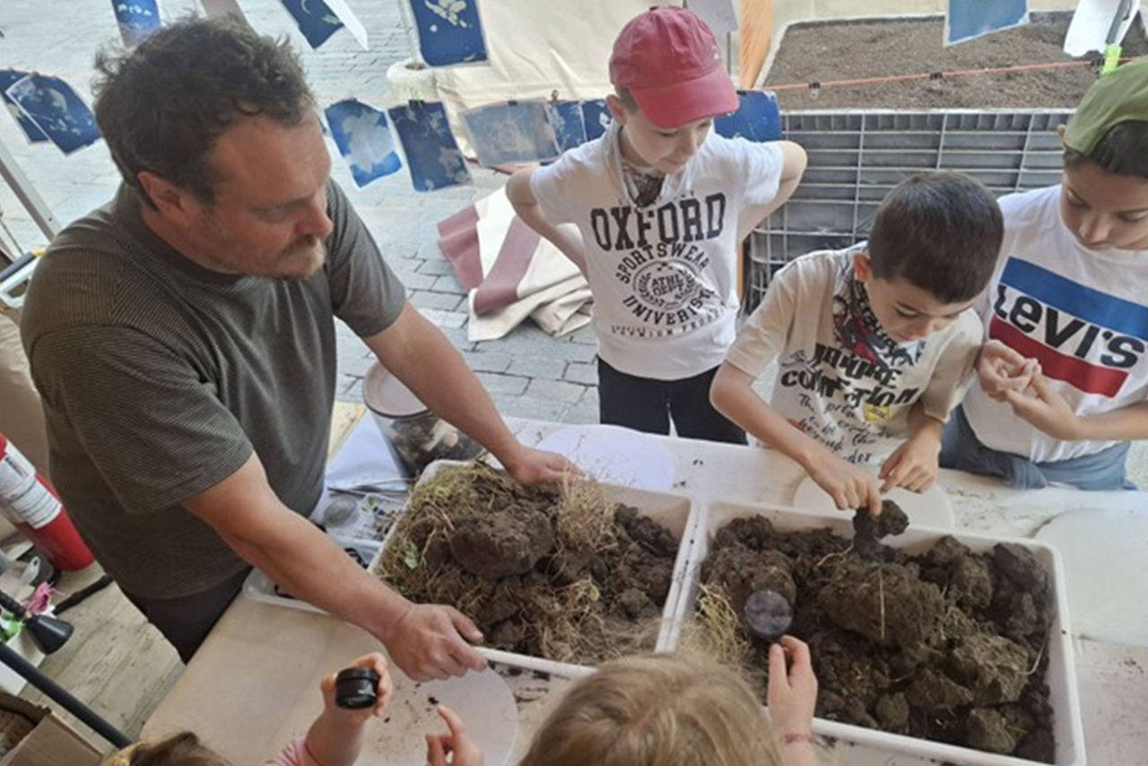 Bambini esplorano vasche piene di terriccio insieme a un esperto.