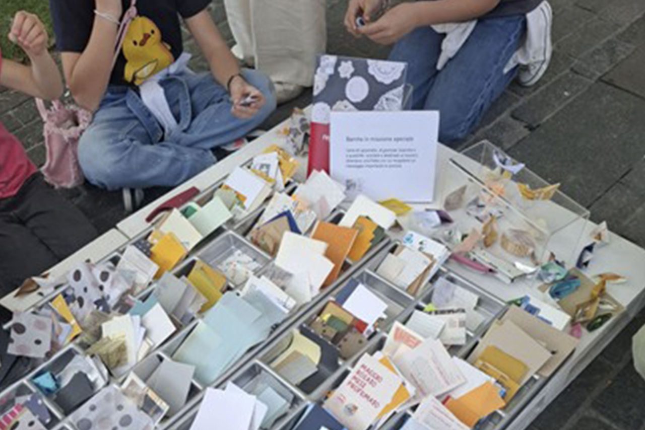 Bambini e bambine partecipano a un’attività di manualità con carta colorata e messaggi ecologici.