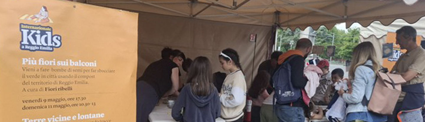 Bambini e famiglie partecipano a un’attività botanica sotto una tenda con il programma esposto.