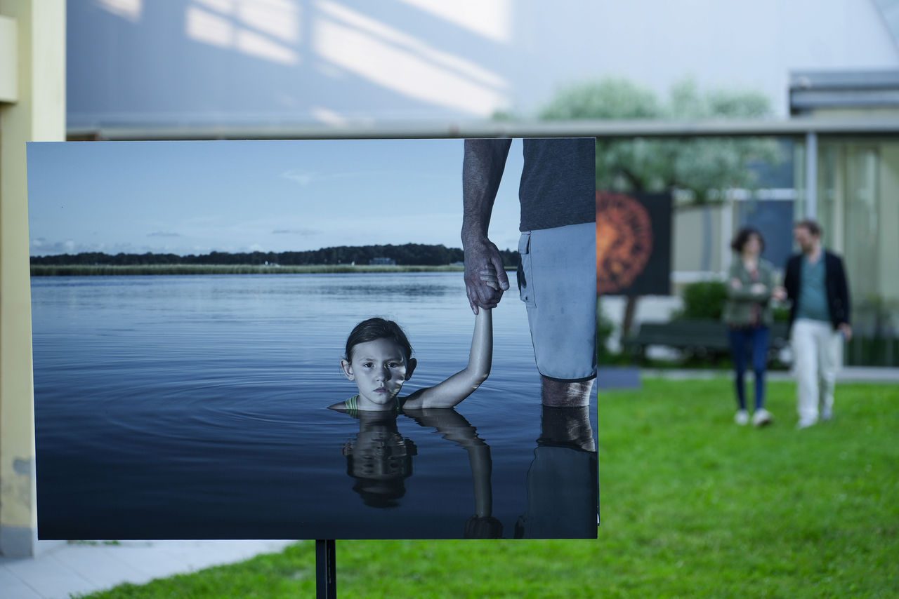 quadro che rappresenta una bambina immersa in un lago che tiene per mano il papà