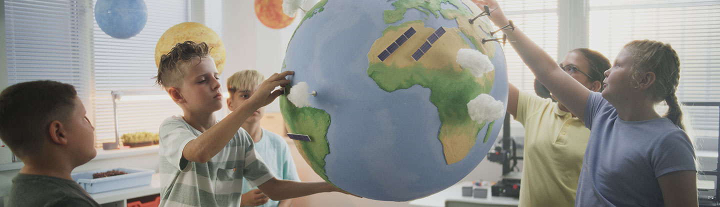 bambini in aula a scuola mentre giocano con un modello della Terra