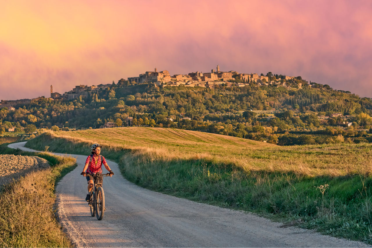donna in bicicletta con panorama delle colline e tramonto sullo sfondo
