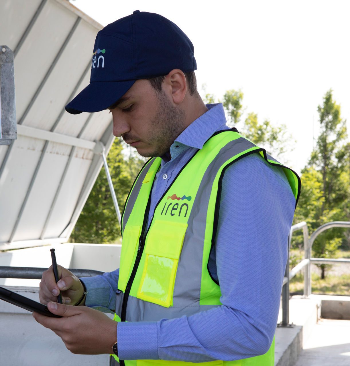 Dipendente Iren con il gilet di protezione utilizza un tablet all'interno di una discarica